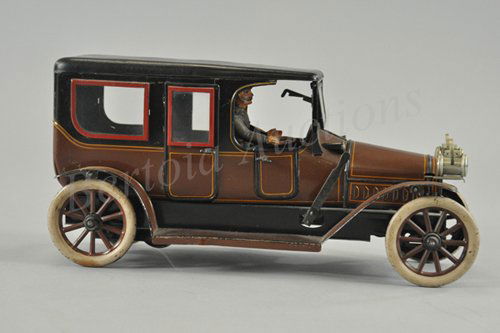 KARL BUB LIMOUSINE: Germany, c. 1912, lithographed tin, done in brown body, black roof, red trim surrounds glass windows, true luxury model with folding front windshield, seated driver, clockwork mechanism. 14" l.