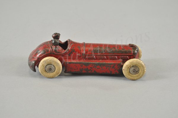 A. C. WILLIAMS RACE CAR: c. 1930's, cast iron, painted in red body, two seated drivers cast at sides of seats, rubber tires, nickel hub caps, long sleek hood. 7" l.