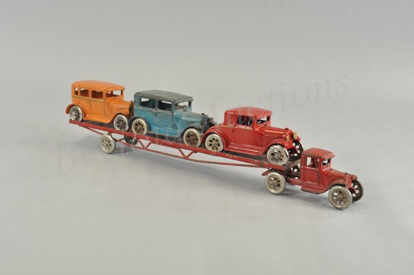 ARCADE MODEL 'A' AUTO TRANSPORT WITH CARS: c. 1930's, cast iron, large scale transporter enclosed red cab, pulls red pressed steel flat bed trailer holding three 6 1/2" vehicles, includes coupe in red, two door sedan in blue and four door seda
