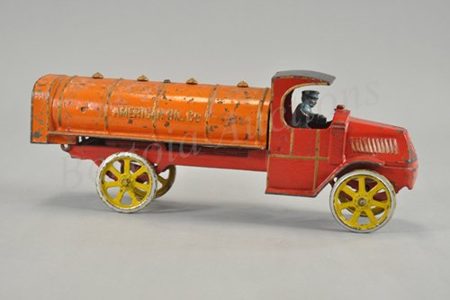 DENT MACK "AMERICAN OIL CO." TRUCK : Cast iron, probably the most colorful of all the oil tankers, done in red Mack "C" cab, black roof, orange tanker body, yellow spoke wheels, blue painted driver, trimmed in gold. 15" l.