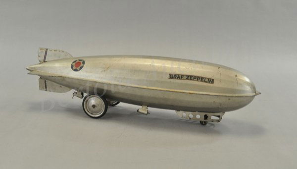 STEELCRAFT 'GRAF ZEPPELIN': c. 1930, pressed steel, painted in silver overall, rubber tires, metal discs, features propellers and clicker noise when pulled, complete decals, moderate playwear. 25 1/4" l.