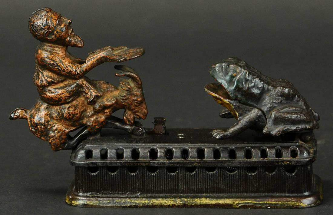 INITIATING SECOND DEGREE MECHANICAL BANK: 865. INITIATING SECOND DEGREE MECHANICAL BANK | Also known as “Goat, Frog and the Old Man,” made by Mechanical Novelty Works of Connecticut, lifting goat’s tail causes spring forward motion and