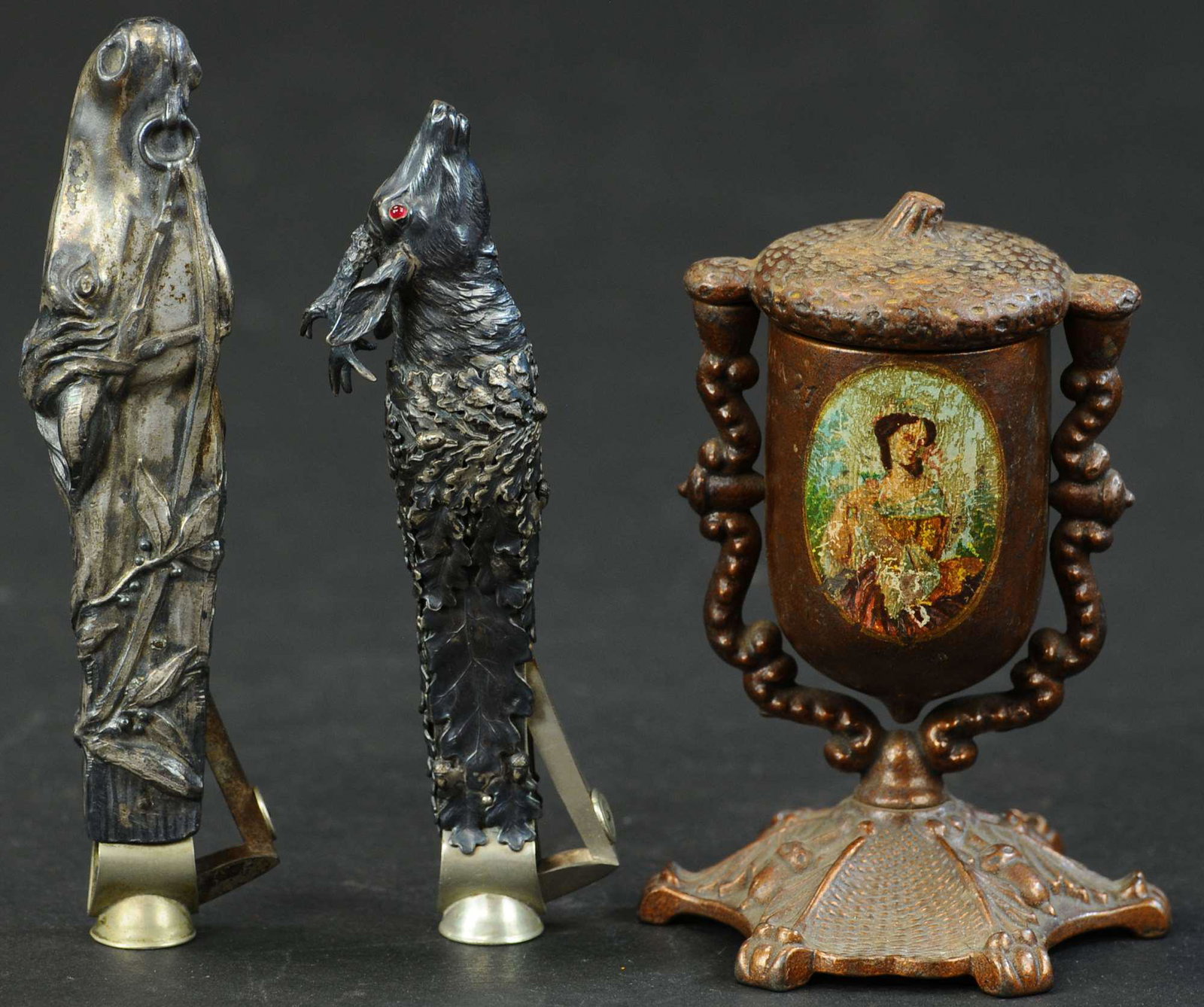 TWO FIGURAL HAND HELD CIGAR CUTTERS & MATCH SAFE: 932. TWO FIGURAL HAND HELD CIGAR CUTTERS & MATCH SAFE | Provenance: The Schroeder Collection. | 5" - 5.75" l. | (Excellent Condition) | $200 - $400