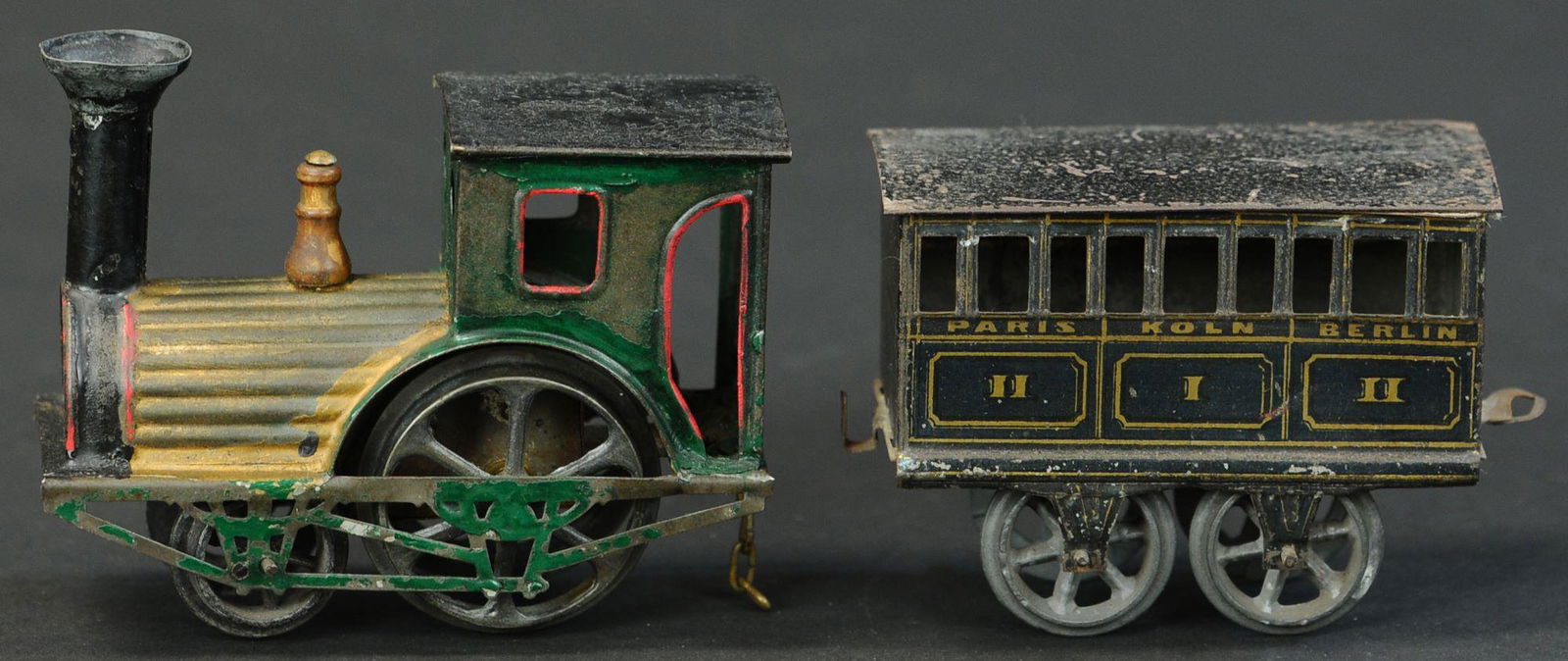 FV LOCO AND PLM COACH: 1435. FV LOCO AND PLM COACH | O gauge, wind-up, hand painted Loco and lithographed coach. | Loco 4" l. | Provenance: Paul Cole Collection. | (Very Good Condition) | $150 - $250