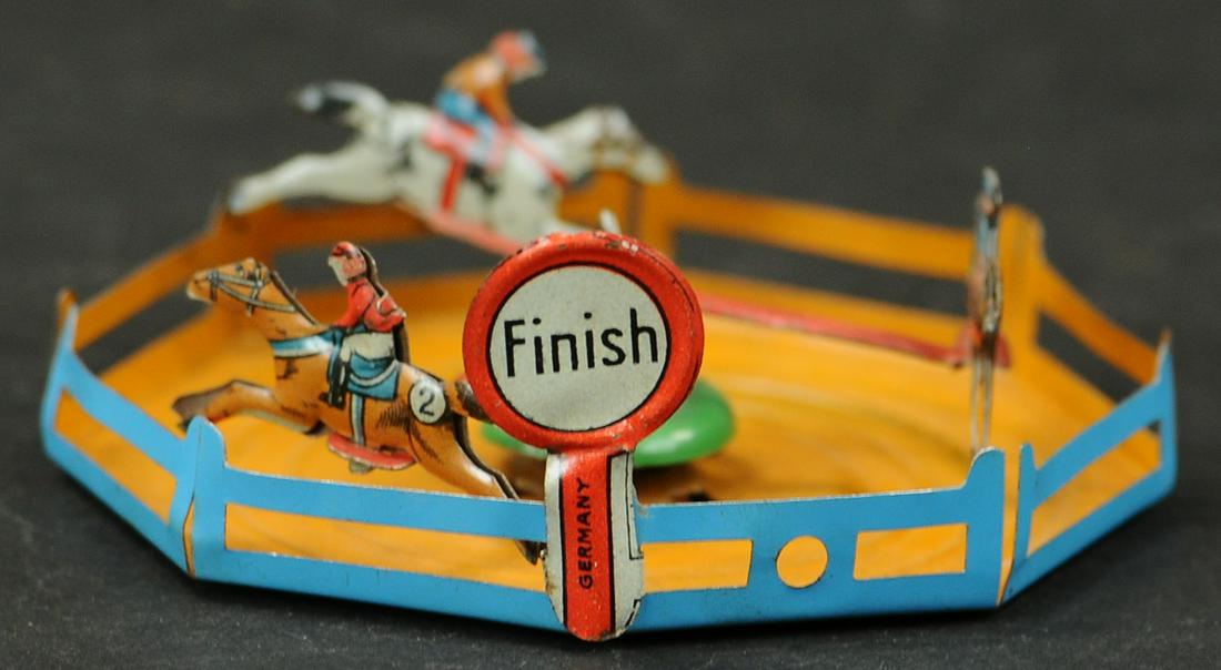 HORSE RACE PENNY TOY: 901. HORSE RACE PENNY TOY | Pulling string causes horses and to seemingly race in a circle. | 3" l. | Provenance: Paul Cole Collection. | (Pristine Condition) | $400 - $600