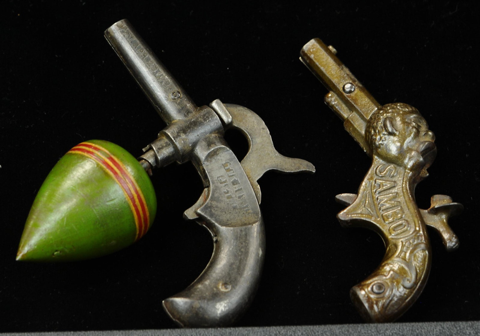 THE ROYAL PISTOL & SAMBO CAP GUNS: 1599. THE ROYAL PISTOL & SAMBO CAP GUNS | Royal pistol when trigger is pressed releases spinning top. Top is wood, usually tin. | 5" l. | (VG - Exc. Cond.) | $600 - $900