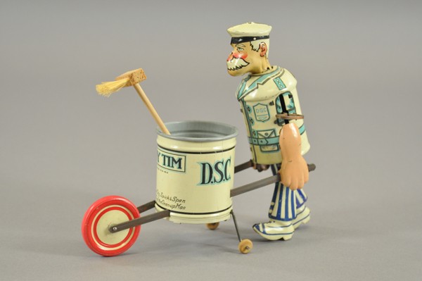 TIDY TIM SWEEPER: Louis Marx, lithographed tin, depicts sanitation worker pushing trash barrel with broom, front reads 'Keep Your City Spick and Span Says Tidy Tim the Clean-Up Man,' key wind operated. 8 1/4" l.