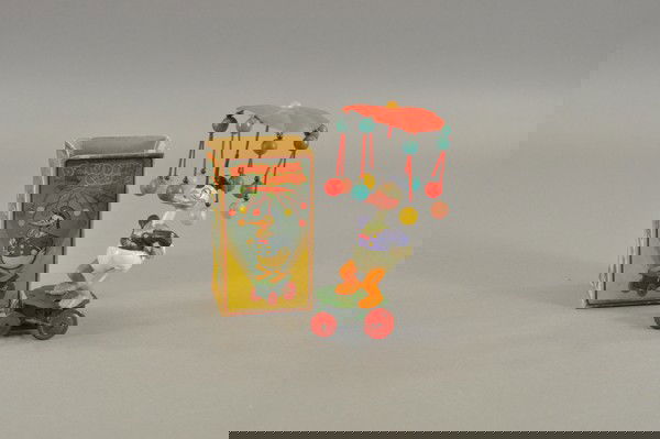 DONALD DUCK CAROUSEL WITH ORIGINAL BOX: Celluloid Donald Duck on tin wheeled platform with spinning celluloid umbrella overhead, wind up mechanism is sprung, in original box. 7 1/2" h.