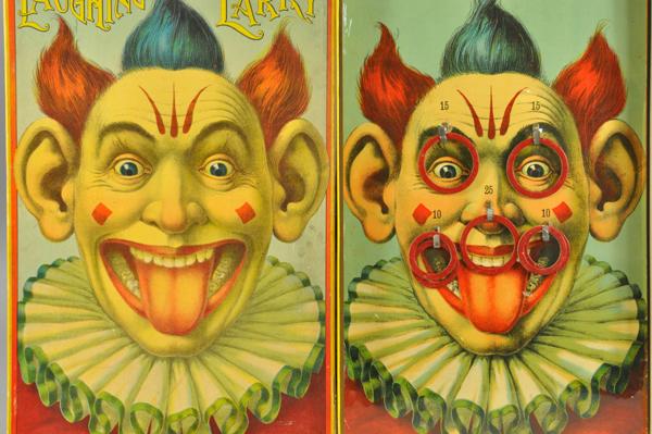 BOXED LAUGHING LARRY RING TOSS GAME: Milton Bradley, bright graphics depict clown with protruding tongue on playing board and box lid; the object being to score points by tossing rings onto various locations on face. Board 12 1/4" x 19 1