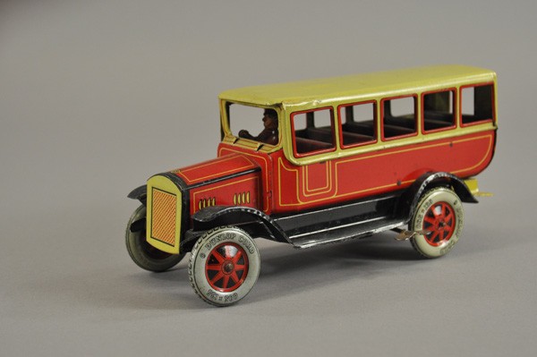 TIPPCO TOURING BUS: Germany, c. late 1920's, lithographed tin, done in red and yellow body, full fenders, seated driver, key wind mechanism, rear litho license plate and steps. 10 1/4" l.