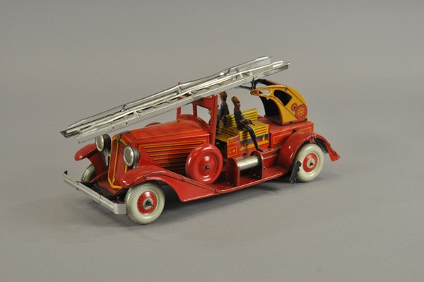 CHARLES ROSSIGNOL LADDER FIRE TRUCK: France, c. 1940, lithographed tin, elaborate toy, many appointments to fire service body, seated fireman, hose reel, extension ladder, spare wheels mounted to fenders, clockwork driven. 14 1/2" l.