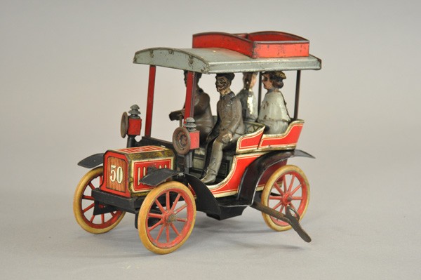 CARETTE 50 TONNEAU: Germany, early teens, lithographed tin, open body features four seated figures, closed rear entry model, headlamps, spoke wheels with rubber tires, clockwork mechanism. 8 1/4" l.