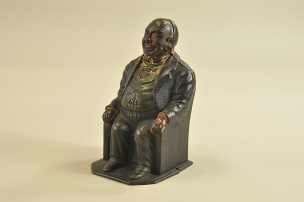 "THE TRUST" STILL BANK: J.&E. Stevens, late 1800's, very scarce example, seated gentleman at chair with base, embossed "The Trust Bank" on green vest, wear to paint, but still an exceedingly desirable still bank for a collec