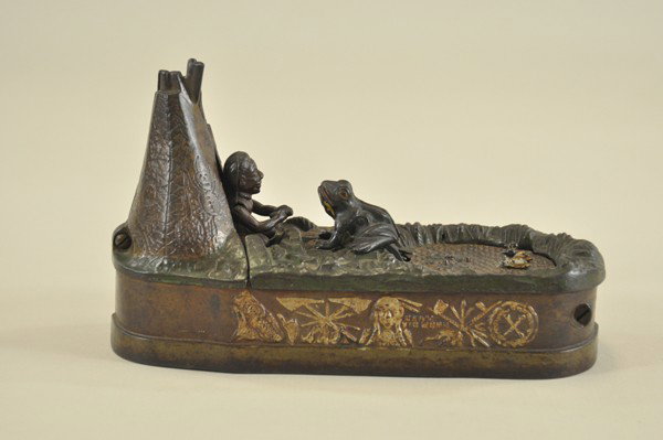 CHIEF BIG MOON MECHANICAL BANK: J & E Stevens Co., designed by Charles A. Bailey, patented 8/8/1899. Place the coin in slot in front of pond, press the lever, and as the coin disappears the frog springs from the water after the fish
