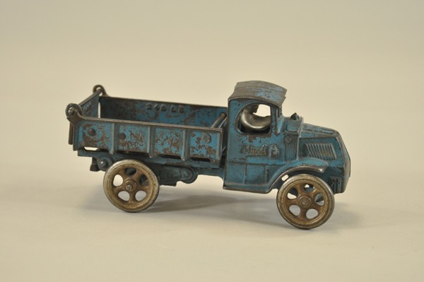 ARCADE MACK DUMP TRUCK: Cast iron, mid size, painted in blue overall, body tilts for unloading, nickel spoke wheels, seated driver, lever on side. 8 1/2" l.