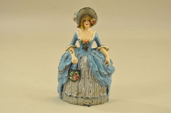 COLONIAL WOMAN DOORSTOP: Littco Products, cast iron, colorful painted variation, charming depiction of elegantly dressed pale blonde woman in blue dress with silver bustle, flowered hat and handbag. 10 3/4" x 5 3/4".