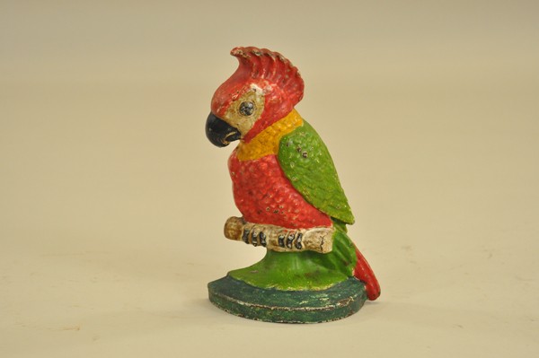 POLLY DOORSTOP: Hubley, depicts colorful parrot in bright red, yellow and green with feather detail, perched on base. 9 5/8" x 9 3/4".