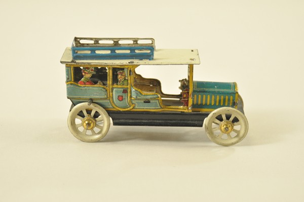 DISTLER SALOON CAR PENNY TOY: Germany, fly wheel operation, colorful vibrant lithography done in blues, yellow, and black, die-cut passengers at windows, JD initials on rear. 4 1/4 l.