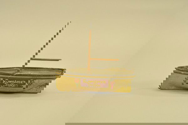 ROWNTREE TOFFEE SAILBOAT CONTAINER: Very scarce, lithographed tin, English toffee tin has images of children on both sides, mast has no sails,deck lifts for retrieval, mast appears re-painted. 7 3/4" l.