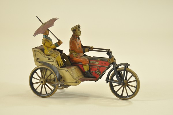 MOTORCYCLE WITH ATTACHED SIDE COACH AND PASSENGER: Greppert & Kelch, Germany, c. 1920, quite interesting lithographed tin cycle with spoked wheels, attached open side with seated lady passenger holding umbrella. 6 1/4" l.