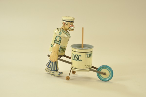 TIDY TIM BY LOUIS MARX: Lithographed tin, mustached man in city worker uniform pushes wheelbarrow style can when activated, includes wooden push broom. 8 1/2" l.