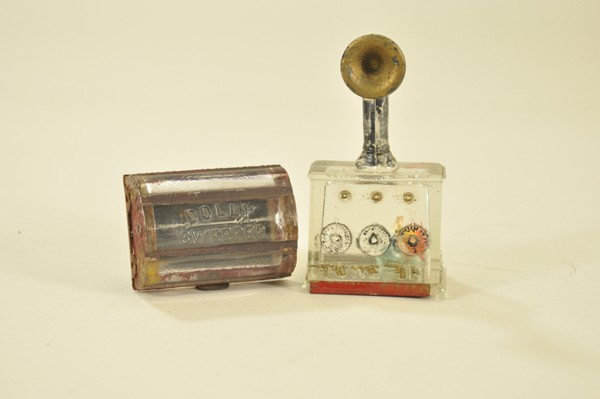 LOT OF TWO GLASS CANDY CONTAINERS: Both highly embossed examples, one depicts old fashioned radio with tuner knobs and speaker on top while the other is an interesting "Dolly Sweeper" base (missing push handle) with decorative swirls o