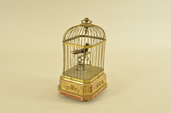 SINGING BIRD AUTOMATON: Clockwork activated, bird on perch sings loudly while turning head side to side and flapping tail feathers, wire cage has carry handle, ornate base. 10 1/2" h.