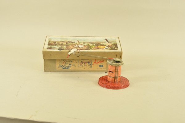 FLYING SEAGULL MECHANICAL TOY: Western Germany, boxed lithographed tin toy, depicts plastic seagull with spread wings able to circle tower with nest graphics on top, clockwork driven. 5" t. x 14" w.