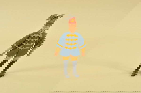 SCHOENHUT LION TAMER: Wood jointed composition head, leather boots, wears blue jackets with yellow trim, and red fez with tassel. 8" h.