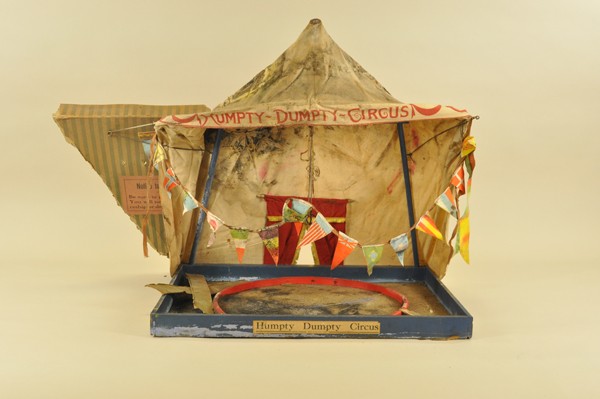 SCHOENHUT REDUCED SIZE CIRCUS TENT: Collapsible menagerie tent with center ring and acrobat performers bars, includes partial original lid, tent has mold and mildew damage, as found, flags of nations appear intact and also moldy, a good
