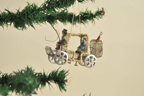 SEBNITZ CARRIAGE CHRISTMAS TREE ORNAMENT: Germany, elaborately detailed wire mesh carriage, driver with black top hat and whip, child sitting in seat, both colorful composition, umbrella in back luggage compartment, cardboard dresden like whe