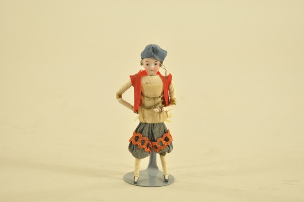 BISQUE HEAD GYPSY GIRL FIGURE ORNAMENT: Crepe paper over cotton with bisque head, blue pants trimmed in orange ric rac, red vest, and blue hat. 4 3/4" t.