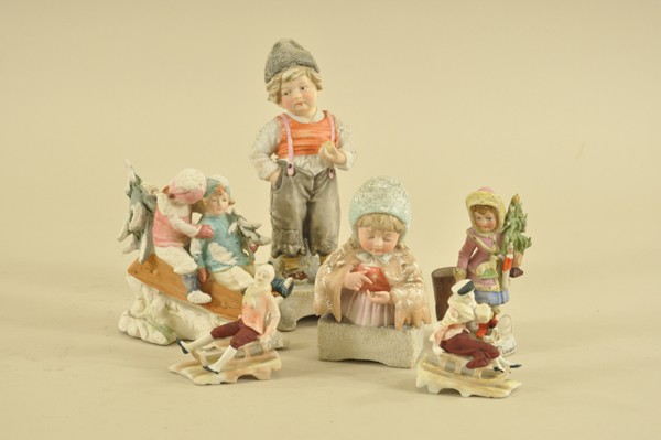 GROUP OF SIX GERMAN BISQUE FIGURES: Charming portrayals of children in everyday life, caped girl counts coins in hand, young boy strolls with apple in hand, sledding kids and more; great details to molds, girl carrying tree is match hol
