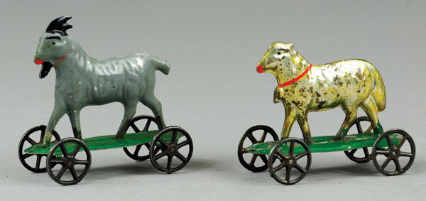 GOAT AND LAMB TIN PULL TOYS: Lot of two small animal platform toys, both hand painted from c. 1880's, includes grey goat and gold spirit finished lamb, both on wheeled green platforms. 3 1/8" to 3 1/4" l.