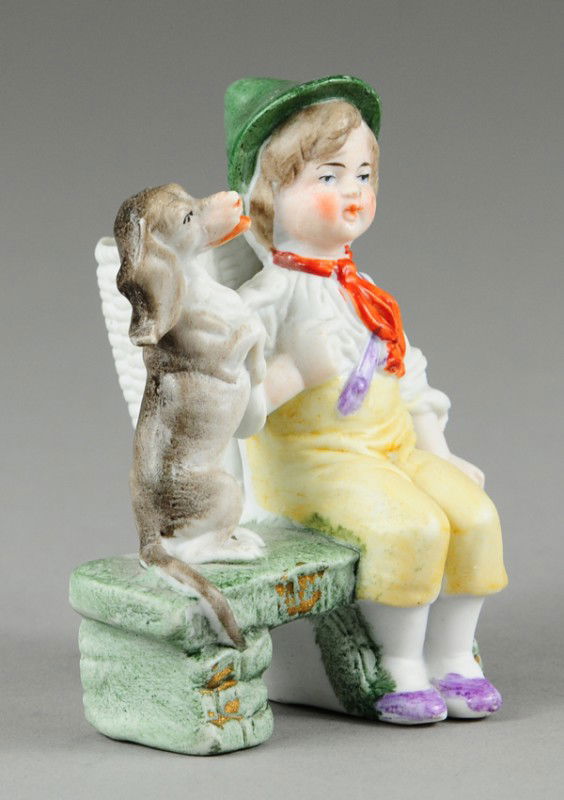SEATED CHILD WITH DOG TOOTHPICK HOLDER: Bisque, c. 1920's, well molded, depicts child seated on bench, dog appears to be quite happy and amused. 3 7/8" h.