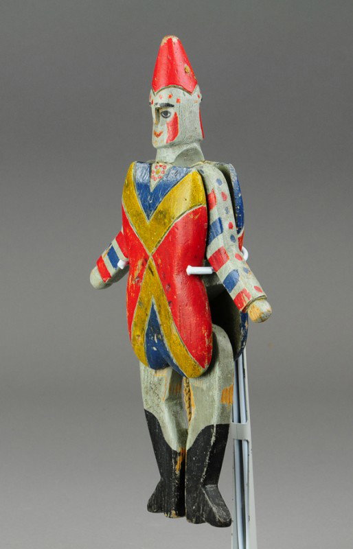 GERMAN CARVED JUMPING JACK: Wood jointed body, polychromed in red, blue and yellow, one leg has script from 1904, as string is pulled clown figure's arms and legs move about. 13" l.