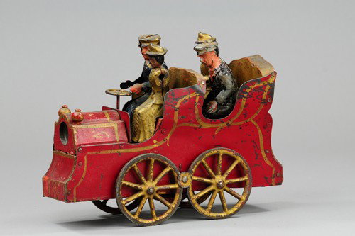 D.P. CLARK HILLCLIMBER: Pressed steel and wood, cast iron spoke wheels, features two hand painted tin figures and two cast iron lady figures, done in red, highlights in gold trim. 10 1/4" l.