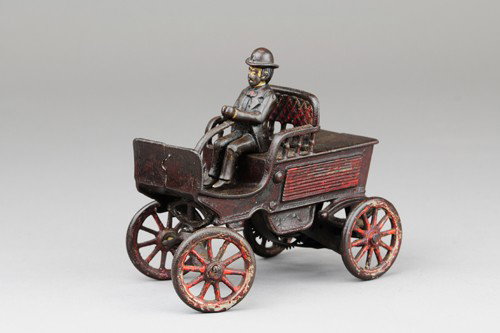 WILKENS EARLY TILLER STEERING CAR WITH DRIVER: Clockwork example, one of the forerunners of the road worthy autos, cast iron, open seating, buckboard dash, spoke wheels, seated driver. 6" l.