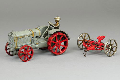 ARCADE MCCORMICK DEERING 10-20 TRACTOR WITH HAY RA: Cast iron, painted in grey with red spoke wheels and hay rake frame, features nickel driver, spoke wheels and tin rakes. 7".