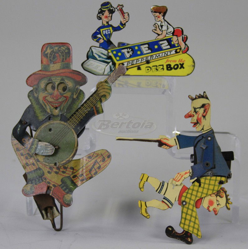 LOT OF THREE HAND HELD TOYS: Lithographed tin, includes a scarce PEZ clicker with die-cut figures, a Leprechaun playing banjo, and man spanking child. 3 1/2" w to 5" h.