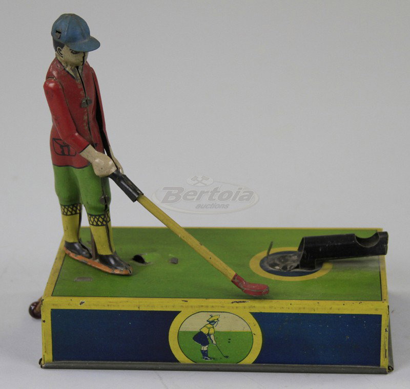 "JOCKO" THE GOLFER TOY: Lithographed tin, knob on side of base allows golfer to swing, figure stands on base tee area, full outfit with hat, includes metal balls. 6 1/2" x 6 1/2".