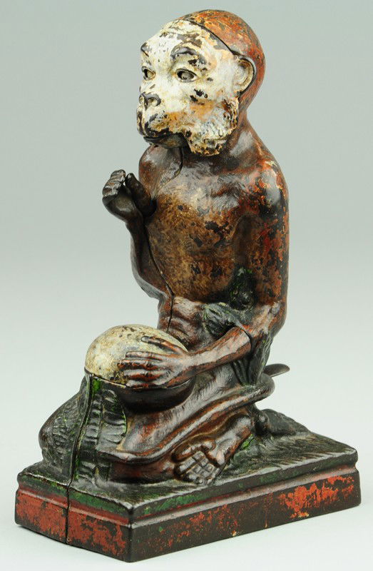 MONKEY AND COCONUT MECHANICAL BANK: J & E Stevens Co., designed by James H. Bowen, patented 3/2/1886. Place a coin in the monkey's hand, press the lever, then he will open the coconut and drop the coin in it; as it falls the movements o