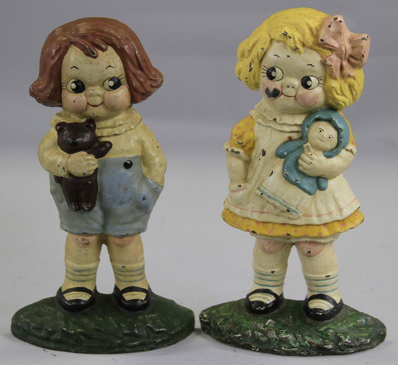 DOLLY DIMPLE & BOBBY BLAKE DOORSTOPS: Hubley, cast iron, lot depicts popular couple in standing pose, one holds Tedder Bear, one holds Baby doll, although considered early repaints, they are very well detailed. Both 9 1/2" h.