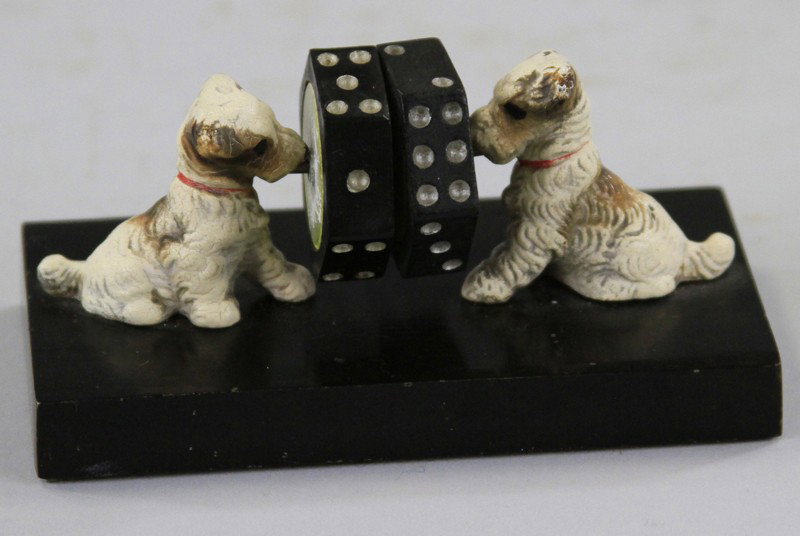 PUPS AND DICE SPINNER: Very unusual dice spinner table display, each able to spin as dogs on sides seemingly hold dice in air by nose, supported on black cast platform. 4 1/8" l.