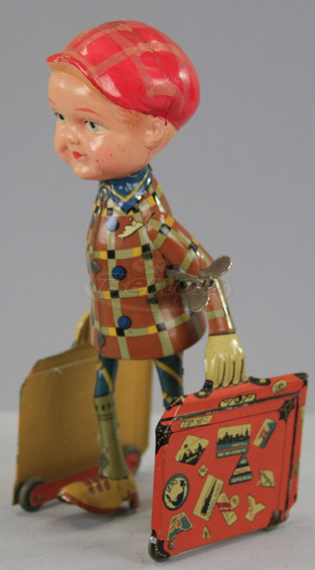 PRE-WAR JAPAN BOY CARRYING SUITCASES: Colorful tin lithography, depicts boy with celluloid head and hat walking along with suitcase in hands, key wind operated, great graphics on case. 8" h.