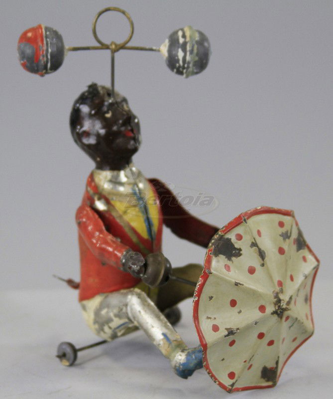 MAN TWIRLING BALLS AND UMBRELLA: Gunthermann, Germany, hand painted tin, seated figure with twirling balls on head and umbrella attached to waist, great clockwork action. 6 3/8" h.