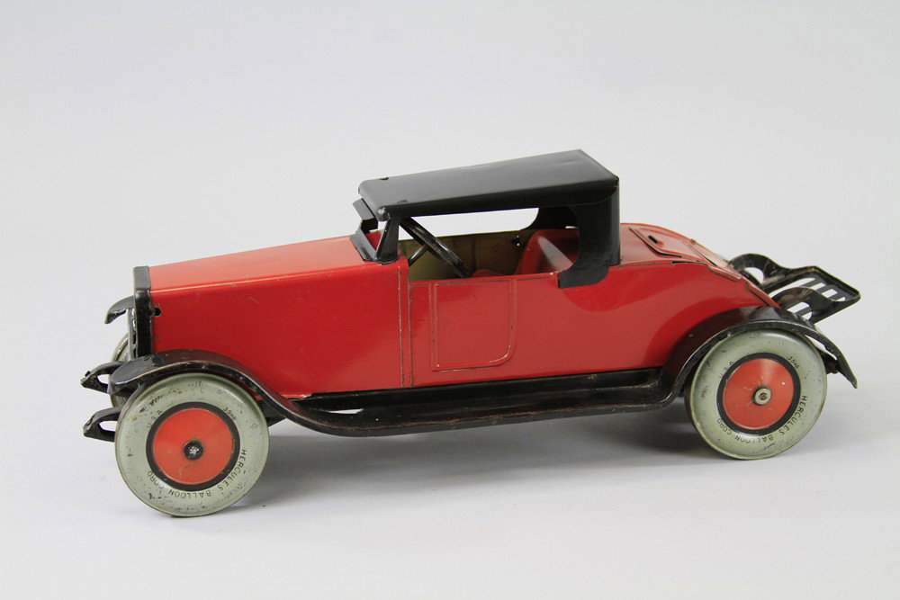 CHEIN HERCULES ROADSTER WITH RUMBLE SEAT: Sleek tin coupe done in red body, black roof, opening rumble seat and foldable luggage rack, large tin balloon wheels. 17 1/2" l.