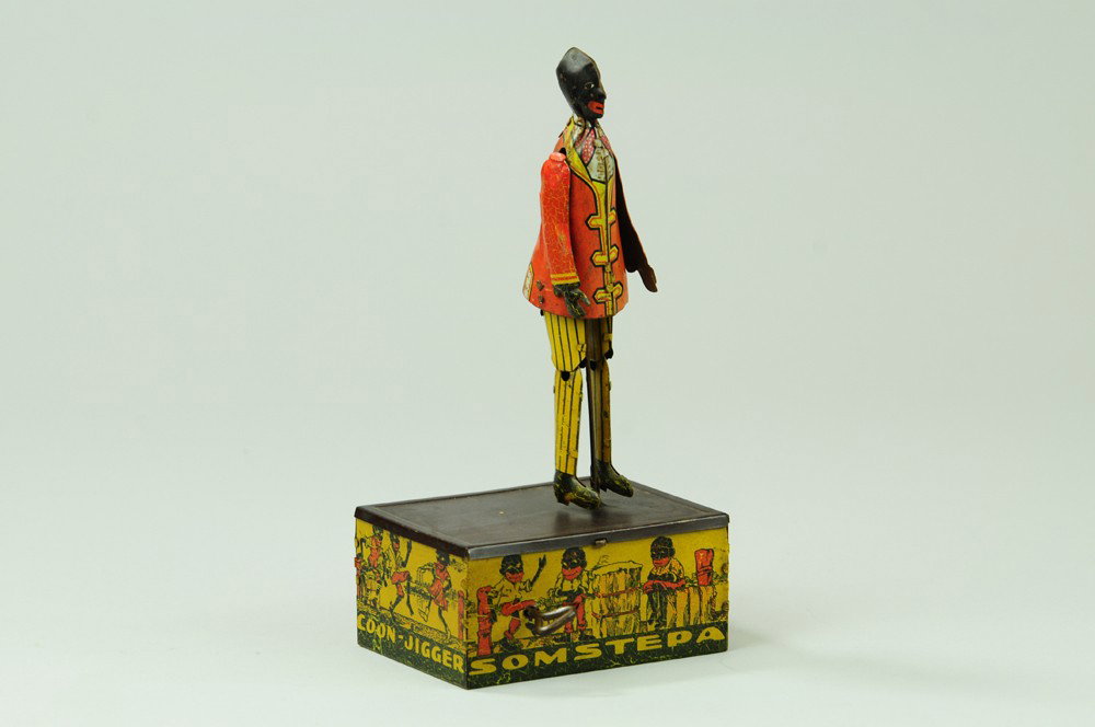 SOMSTEPA JIGGER: Marx, lithographed tin, depicts dancing figure on square base, very colorful graphics, clockwork mechanism. 8" h.