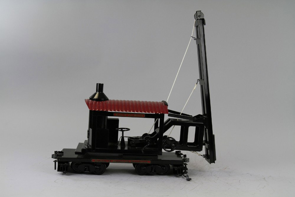 BUDDY 'L' T-PRODUCTION LOCOMOTIVE PILE DRIVER: Outdoor Railroad piece, black housing frame with boiler, red corrugated roof, tall guide rail contains weight, lever controlled, flat car body has four wheel trucks stabilizer extensions at each end, 