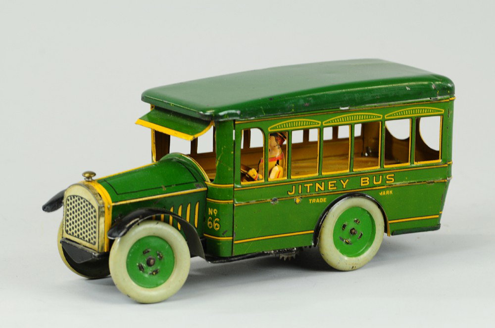 STRAUSS JITNEY BUS: Lithographed tin, done in green with yellow highlights, seated driver, well detailed, wind up action. 9 1/4" l.